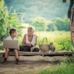 A picture of a woman and grandson with a computer.