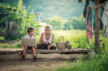 A picture of a woman and grandson with a computer.